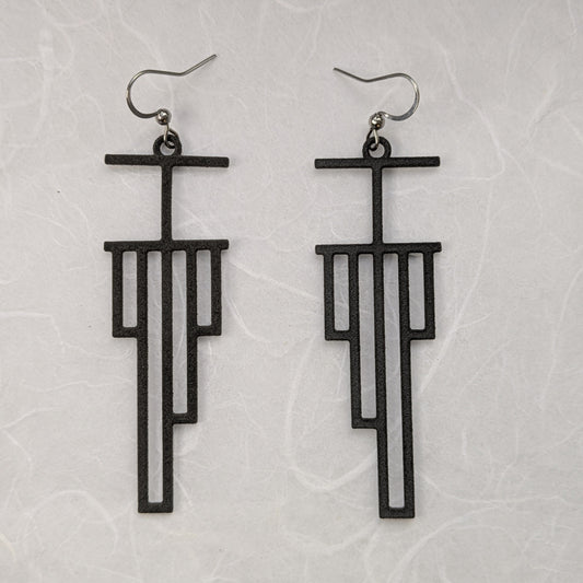 Black geometric earrings on a light gray textured background
